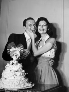 Frank Sinatra and Ava Gardner, standing behind their wedding cake on their wedding day.